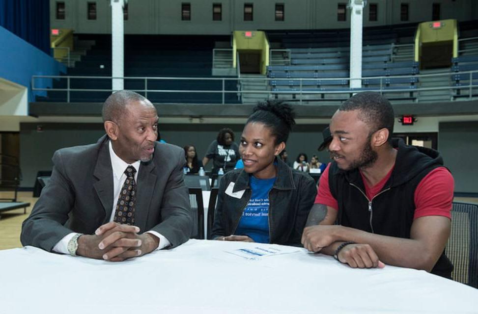 Three people sit talking at a table in the CGC 