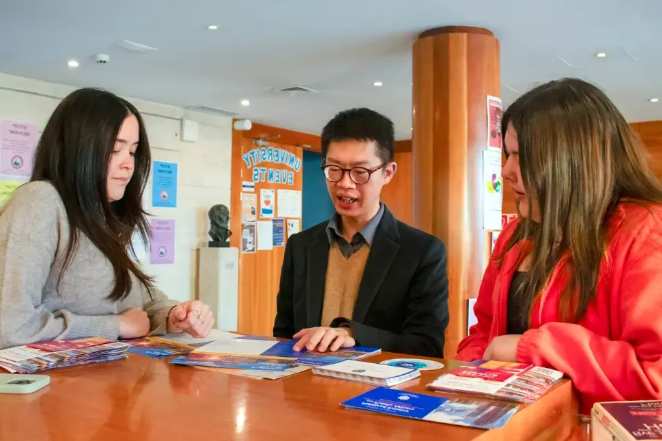 3 people consult information brochures in a building lobby.