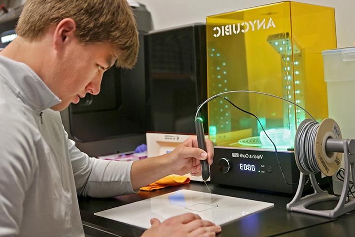 Student using 3D printer in engineering lab