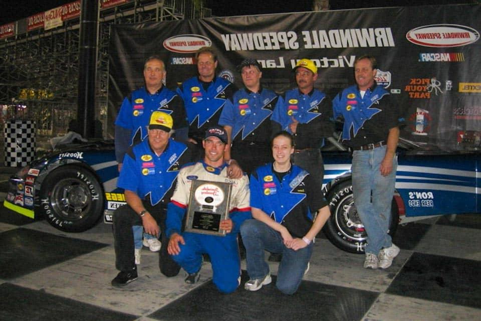 Sullivan poses with her pit crew team in front of a race car